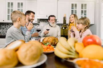 Thanksgiving Celebration Tradition Family Dinner Concept. Happy smiling family clinking glasses of wine and juice on holiday dinner