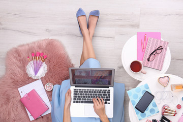 Beauty blogger with laptop and cosmetics sitting on floor, top view - obrazy, fototapety, plakaty