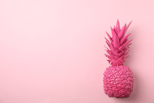 Painted pink pineapple on color background, space for text