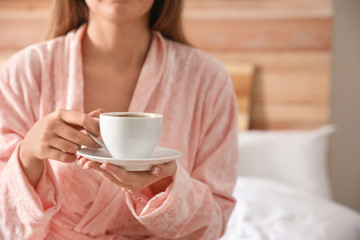 Woman with cup of hot coffee at home, closeup