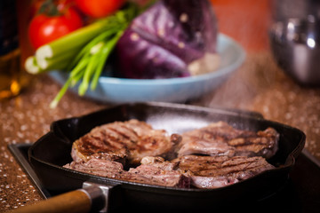 grilled steak in a frying pan on a background of vegetables