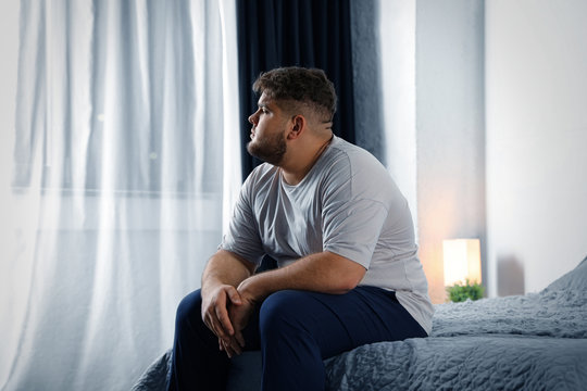 Depressed overweight man on bed at home