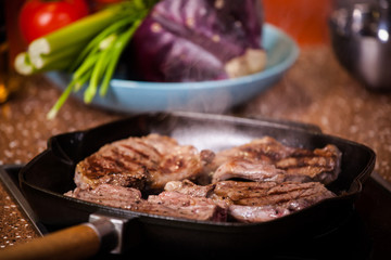 grilled steak in a frying pan on a background of vegetables