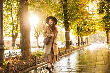 Portrait of attractive woman wearing coat and hat walking in autumn park