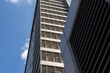 Fototapeta na wymiar Tall building is shot from below. Blue sky and skyscraper and copy space. Horizontal and vertical lines as part of a multi-story building