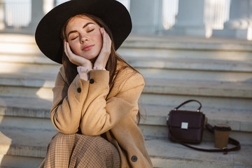 Portrait of seductive young woman sitting on building stairs outdoors
