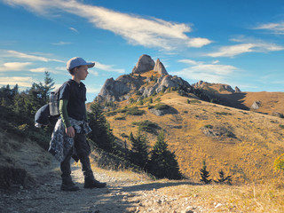 Obraz premium Little boy with backpack hiking in scenic mountains