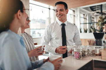 Smiling young office workers talking together over coffee