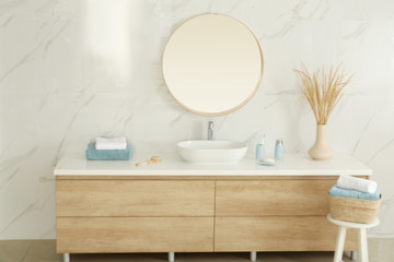 Fototapeta na wymiar Round mirror over vessel sink in stylish bathroom interior