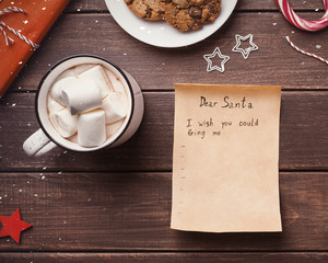 Wish list letter to Santa claus from child on wooden background