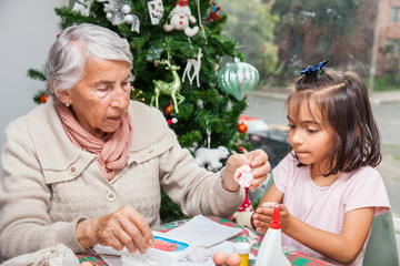 Little girl having fun while making christmas Nativity crafts with her grandmother - Real family