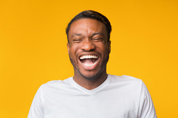 Portrait Of Laughing Black Man Standing Over Yellow Background, Studio
