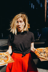 Young girl holding two pizzas
