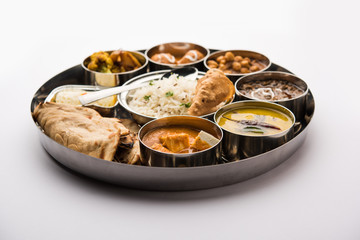 Indian vegetarian Food Thali or platter includes paneer butter masala, dal makhani / tarka, chole papad, kofta curry, gulab jamun, aloo-gobi sabji, chapati and rice with Bengali sweet served