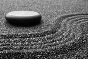Fototapeta na wymiar Zen garden stone on black sand with pattern, closeup