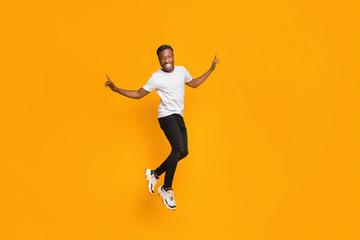 Fototapeta na wymiar Joyful Afro Guy Jumping In Air Having Fun, Studio Shot