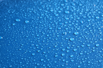 Naklejka na ściany i meble Water drops on blue background, closeup view