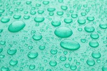 Water drops on turquoise background, closeup view