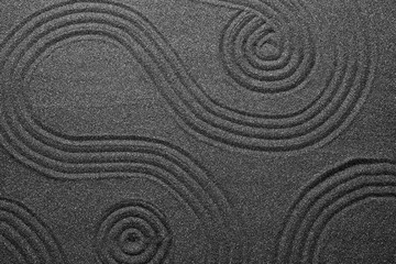 Pattern on decorative black sand, top view. Zen and harmony