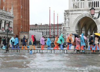 people with umbrellas and raincoat in the rainy day on the walkw