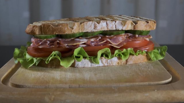 large sandwich with bacon, tomato, cucumber and salad