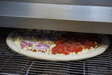 Preparing pizza in oven at restaurant kitchen