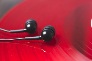 Obraz na płótnie Canvas Black vacuum headphones lie on a red vinyl record.