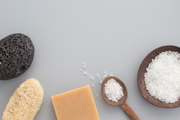 Natural bath products - sea salt, pumice, sponge, soap - on gray background. Spa, healthcare concept. Top view, flay lay, copy space