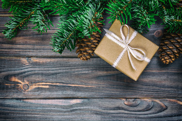 Christmas composition background. Christmas gift with pine cones and fir branches on wooden background. Flat lay, top view, copy space. Toned