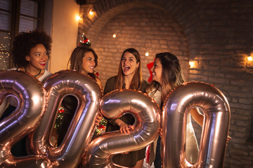 Obraz na płótnie Canvas Girlfriends at New Year party holding balloons 2020