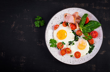 Fototapeta na wymiar Plate with a keto diet food. Fried egg, ham, spinach, and tomatoes. Keto, paleo breakfast. Top view, copy space