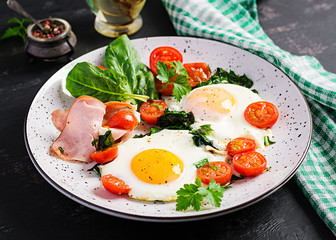 Plate with a keto diet food. Fried egg, ham, spinach, and tomatoes. Keto, paleo breakfast.
