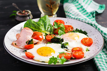 Plate with a keto diet food. Fried egg, ham, spinach, and tomatoes. Keto, paleo breakfast.