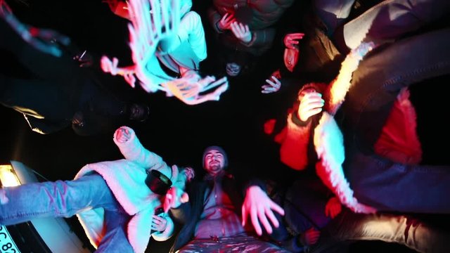 Group of funny friends in circle hip hopping and gesturing hands having fun outdoors at night. Bottom view.