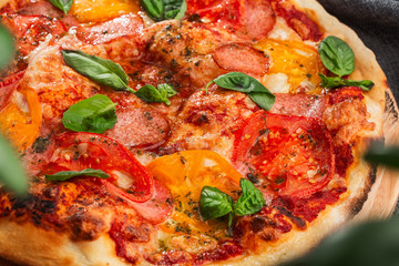 Delicious hot homemade pizza on the wooden table. Pizza - Fresh homemade pizza with pepperoni, cheese and tomato sauce, tomatoes, and basil with copy space. Horizontal