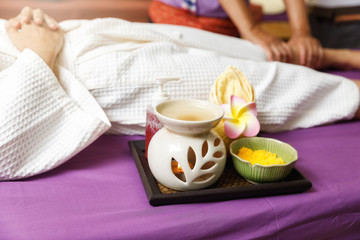 Skin care products set with woman receiving leg massage service from masseuse in thai spa and massage shop.