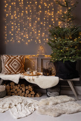 Wooden bench stand in corner of room. Fir in black basket stand on it and firewood lays under it