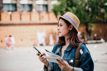 Female young Asian traveler with backpack and photocamera in the old town market square, sightseeing in the chiangmai Road outdoor market in chiangmai, Thailand