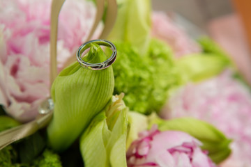 Obraz na płótnie Canvas wedding rings lie on a beautiful bouquet as bridal accessories