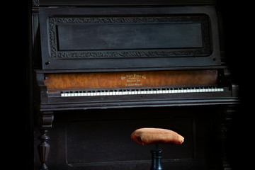 Fototapeta na wymiar old black upright piano with bench with black background
