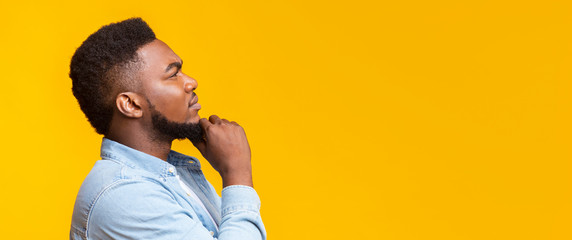 Thoughtful african man touching his beard and looking at copy space