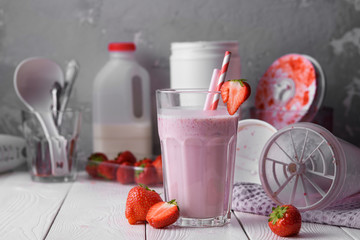Strawberry protein shake on a white wooden background. Fresh milkshake with strawberries on a light table. A glass of strawberry smoothie.