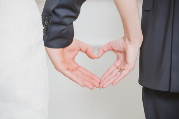 wedding couple showing shape of heart from their hands.