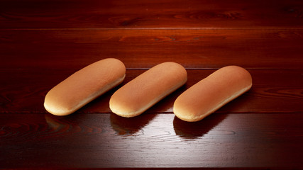 Hot dog buns on a brown background from varnished wooden boards.