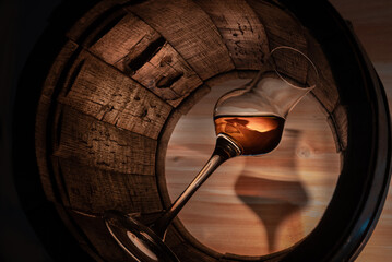 a glass of whiskey in an oak barrel - obrazy, fototapety, plakaty