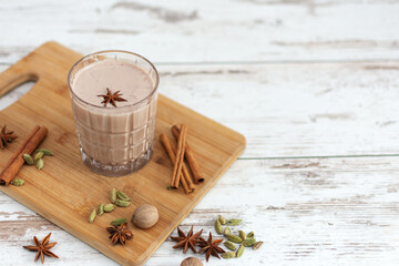 Masala chai made by brewing black tea with aromatic spices and herbs, such as Cinnamon Stick, Thai Cardamom, Ginger, Star Anise, Black Peppercorns and Black Tea. - obrazy, fototapety, plakaty