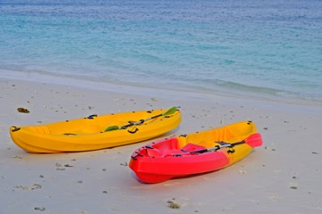 Colorful kayak on the beach with blue sea as background.