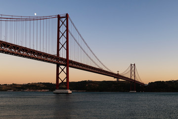 View of the 25 of April Bridge (Ponte 25 de Abril) over the Tagus River, in the city of Lisbon, Portugal; Concept for travel in Portugal