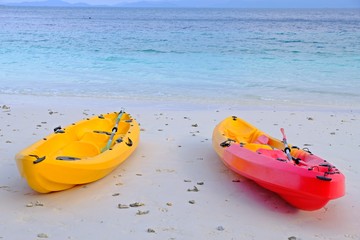 Colorful kayak on the beach with blue sea as background.