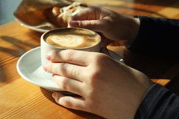 Woman with cup of fresh aromatic coffee at table in cafe